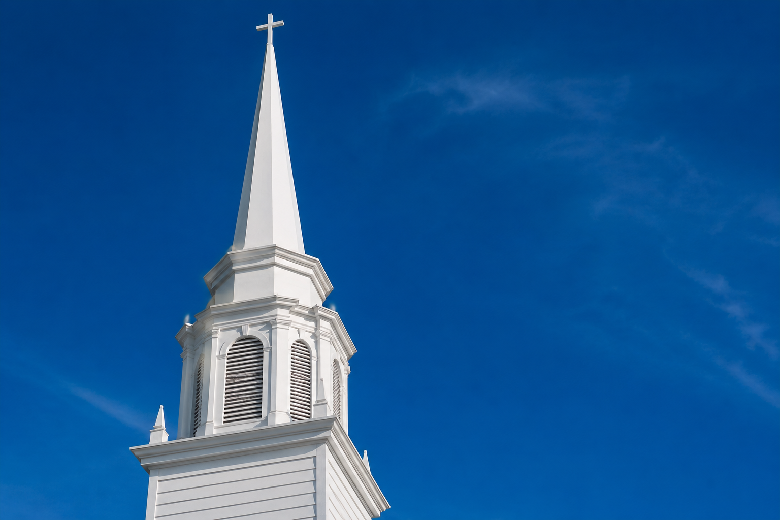 The white steeple of First Congregational Church of Clarkston against a deep blue sky